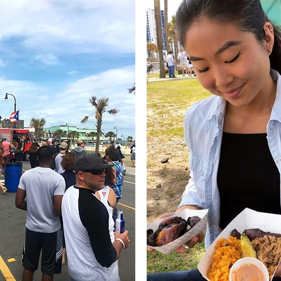 A crowd queues at a red food truck while a woman holds plates of grilled meat, rice, beans, and sauce outdoors.